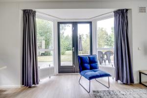 a blue chair in a room with a window at 4 - Person Lakeside 47 Bungalow in Ewijk
