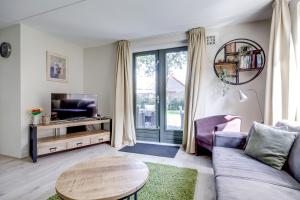 a living room with a couch and a tv and a table at 6 - Persons Lake Area 40 Bungalow in Ewijk