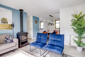 a living room with blue chairs and a fireplace at 5 - Person Forest 239 Sauna Bungalow in Ewijk