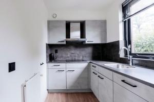 a kitchen with white cabinets and a sink and a window at 6 - Persons Lakeside 7 Bungalow in Ewijk +22 photos