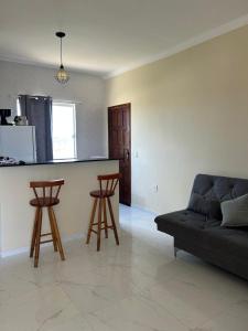a living room with a couch and two bar stools at Ventos de Arubinha - Apto Inteiro - Reserva a partir de 04 dias em Janeiro e Fevereiro in Arraial do Cabo +23 photos