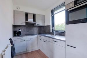 a white kitchen with a sink and a window at 6 - Persons Lakeside 25 Bungalow in Ewijk