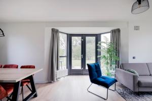 a living room with a table and a blue chair at 6 - Persons Lakeside 25 Bungalow in Ewijk