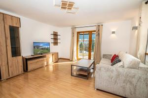 a living room with a couch and a flat screen tv at Mazot Ferienhaus Kleinwalsertal in Riezlern