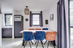 a kitchen and dining room with a white table and blue chairs at 6 - Persons Lakeside 61 Bungalow in Ewijk