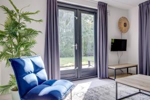 a living room with a blue chair and a sliding glass door at 6 - Persoons Forest 67 Bungalow in Ewijk +39 photos