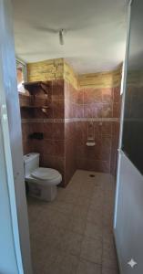 een badkamer met een toilet en bruin betegelde muren bij Casa El Limón in Zihuatanejo