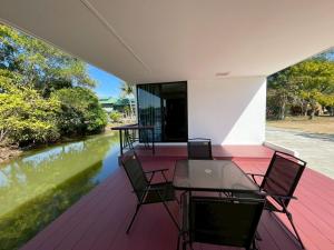 a deck with a table and chairs next to a river at The Lakefront Collective in Buriram, Thailand in Ban Nong Muang