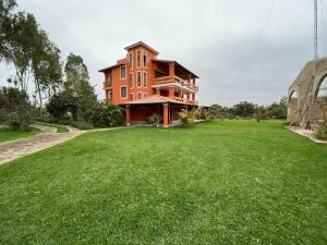 a large house with a green lawn in front of it at La Casona - Hospedaje Campestre in El Carmen