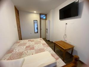 a bedroom with a bed and a tv on the wall at La Casona - Hospedaje Campestre in El Carmen