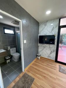 a bathroom with a toilet and a tv on a wall at The Lakefront Collective in Buriram, Thailand in Ban Nong Muang +84 photos
