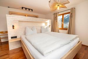 a large white bed in a room with a window at Mazot Ferienhaus Kleinwalsertal in Riezlern