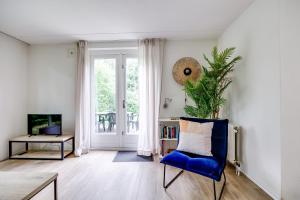 a living room with a blue chair and a window at 6 - Persoons Forest 209 Bungalow in Ewijk
