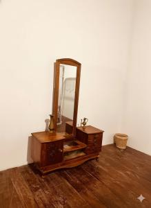a wooden dresser with a mirror on a wooden floor at Charlotte's Coral Breeze - A Colonial Seaside Bungalow in Hikkaduwa