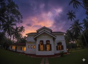 a white house with palm trees in front of a sunset at Charlotte's Coral Breeze - A Colonial Seaside Bungalow in Hikkaduwa +9 photos