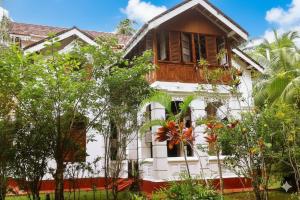 a white house with trees in front of it at Charlotte's Coral Breeze - A Colonial Seaside Bungalow in Hikkaduwa