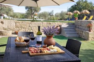 a table with a plate of food and wine at Nature House Lagos do Sabor in Torre de Moncorvo