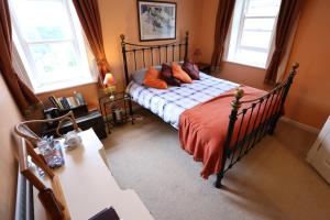 バリーキャッスルにあるCorratavey Guest Accommodationのベッドルーム1室(オレンジ色の毛布、窓2つ付)