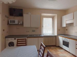 a kitchen with white cabinets and a table and a microwave at Appartamenti LITEGOSA casa vacanza 1 in Panchià