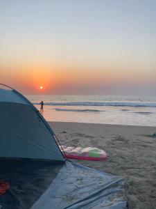 a tent on the beach with the sunset in the background at Bush Baby Compound in Gunjur
