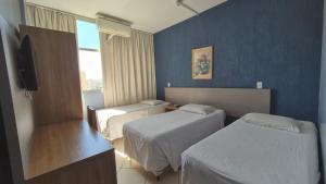 瓦拉达里斯州长市Realminas Hotel e Restaurante的一间有两张床和一台电视的酒店房间