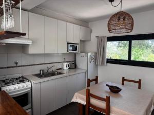 a kitchen with white cabinets and a table and a sink at La Morondanga in Villa Yacanto