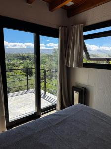 a bedroom with a bed and a large window at La Morondanga in Villa Yacanto