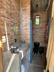 a bathroom with a toilet and a brick wall at KAO Cabin in Brisas de Zicatela