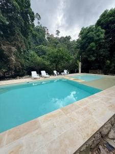 a swimming pool with two chairs and a table at Finca Campestre - Villa Esther con Piscina en Mesitas del Colegio in El Colegio