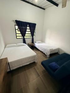 a bedroom with two beds and a blue couch at Finca Campestre - Villa Esther con Piscina en Mesitas del Colegio in El Colegio