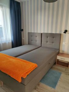 a bed with an orange blanket on it in a room at Apartament Charlie in Darlowko