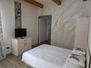 una camera da letto con un letto bianco e una televisione di Cabana OAZA AMURG a Runcu