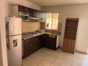 a kitchen with a white refrigerator and brown cabinets at Casa Completa Cómoda en el Sur in Santa Gertrudis