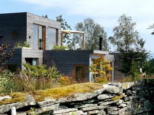 a house on a hill with a stone wall at FjordView Sanctuary in Nedstrand