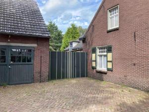 a brick house with a gate and a brick driveway at Het werkhuis, terug in de tijd in Uden