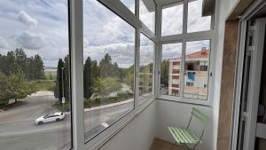 a room with a window with a green chair and a car at Park Apartment - 2 Room APT in Lavradio