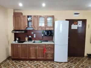 a kitchen with wooden cabinets and a white refrigerator at Апартамент почивка в планината in Pamporovo +11 photos
