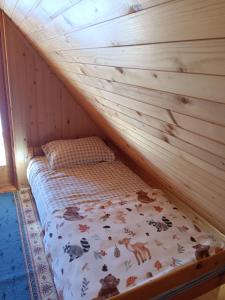 a bed in a room with a wooden wall at Vikendica za odmor in Vlasic