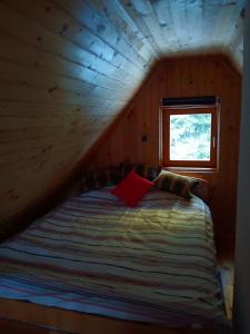 a bed in a wooden room with a window at Vikendica za odmor in Vlasic