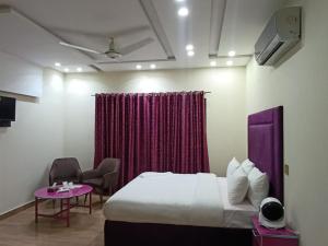 a hotel room with a bed and a purple curtain at Emporia Hotel & Suites in Lahore
