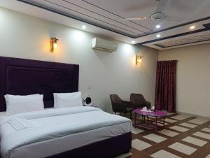 a bedroom with a bed and a table with chairs at Emporia Hotel & Suites in Lahore