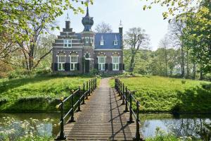 a house on a hill with a bridge over a body of water at B&B Stinzenflora - Gezellige accommodatie tussen groen en historie in Cornjum
