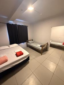 a room with two beds and a chair in it at Cerrado Hostel in Goiânia