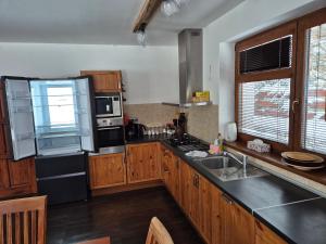 a kitchen with wooden cabinets and a black refrigerator at Chata Marta in Boží Dar