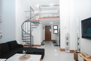 a living room with a black couch and a spiral staircase at Woodlands Condotel in Bulan