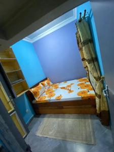 ein kleines Bett in einem Zimmer mit blauen Wänden in der Unterkunft Le Centurion in Brazzaville