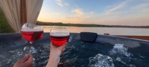 two people are holding wine glasses in a tub at Wilczy Domek nad Witką in Wilka