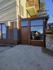 a house with a large glass door with a balcony at Apartmani Planinsko srce Vlašić in Vlasic