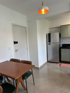 a kitchen with a wooden table and a refrigerator at Apartamento 2 Quartos com Ar Condicionado in Paraty