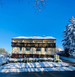 ein schneebedecktes Gebäude mit einem Baum in der Unterkunft Haus PANORAMA - Appartement Auszeit 3 in Braunlage